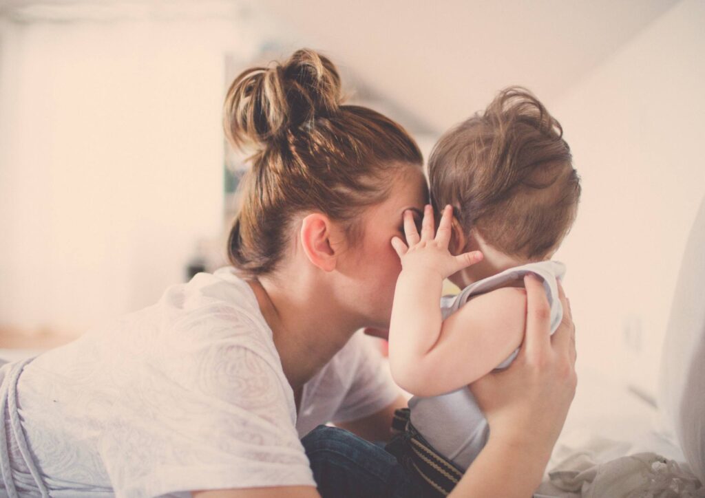 A parent holding a baby close in a quiet, tender moment, symbolizing the emotional weight and responsibilities of motherhood.
