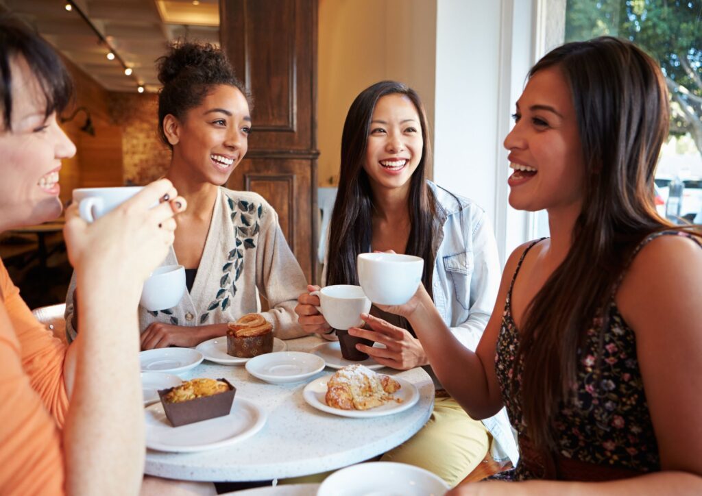 Friends sharing coffee and pastries in a cozy café — a simple moment that reflects the warmth of chosen family.