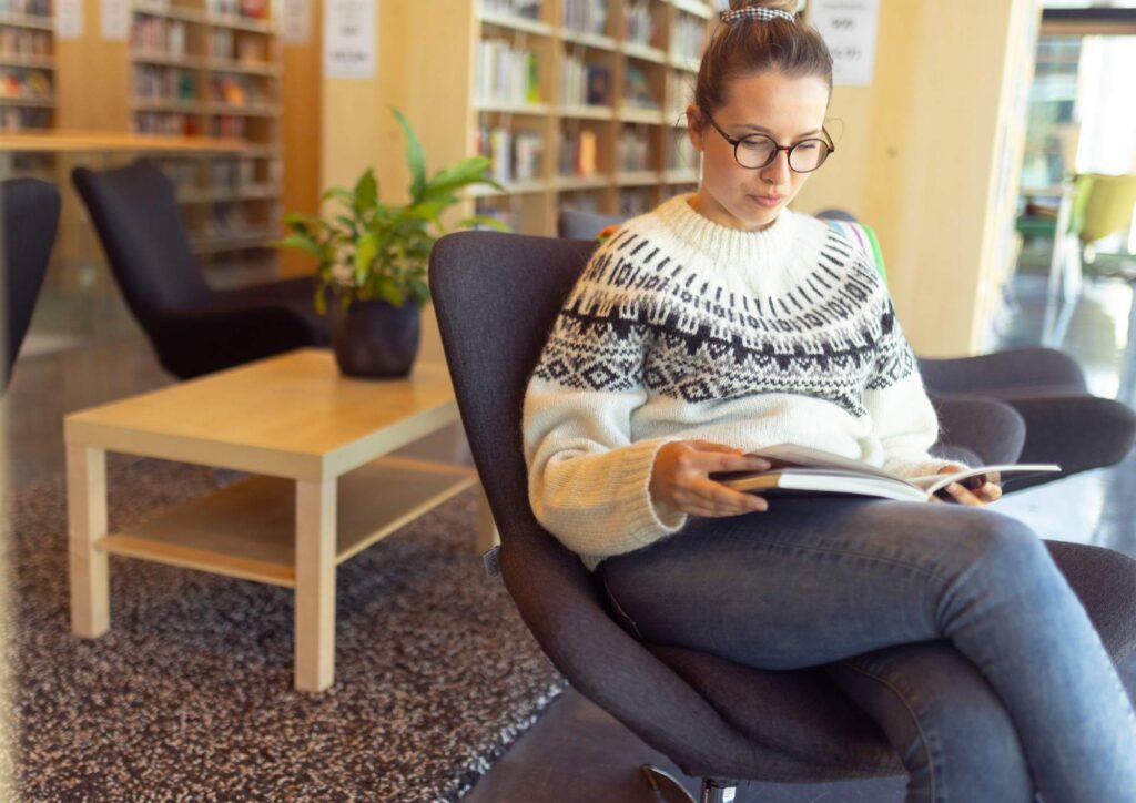 A woman reading in a calm, modern library — a quiet moment of everyday connection.