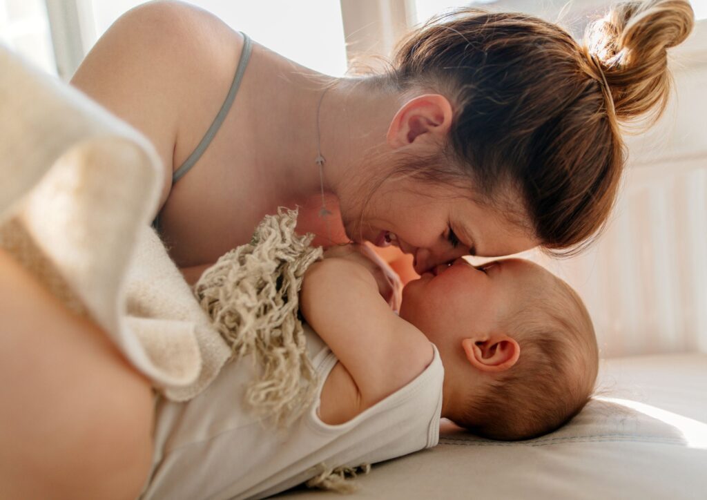 Parent and toddler sharing a quiet morning cuddle, touching noses and resting together in soft natural light.