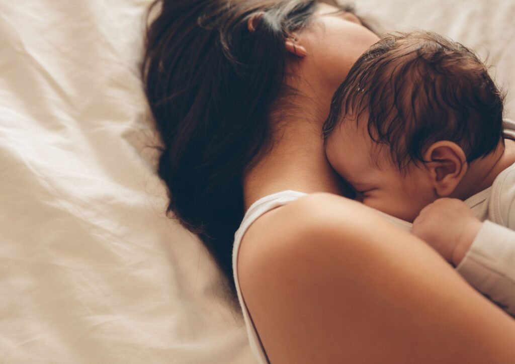 A baby resting peacefully on an adult’s shoulder, eyes closed, showing closeness and tenderness in the early newborn stage.
