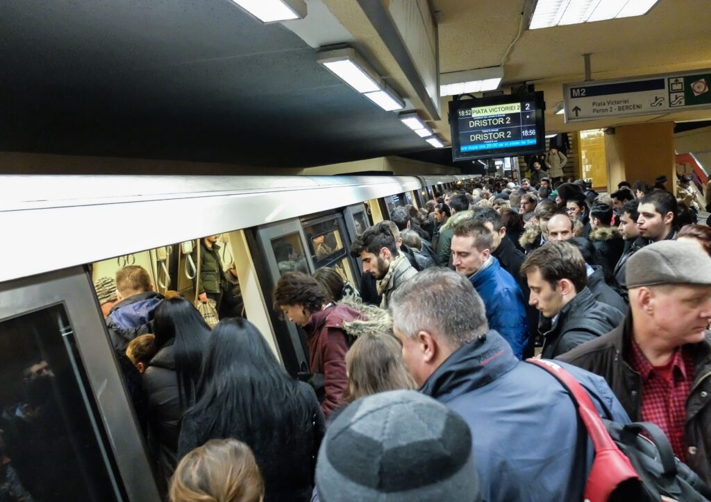 A packed subway platform with commuters boarding a train during rush hour, representing the daily routine and monotony of commuting.