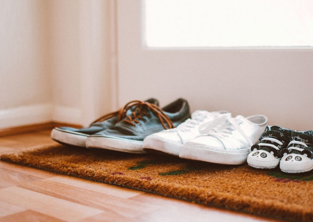 Adult and child's shoes placed side by side near a doorway.